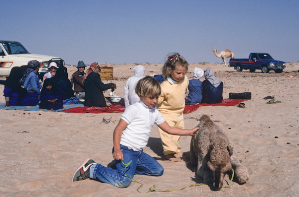Young boy and girl admiring orphaned camel